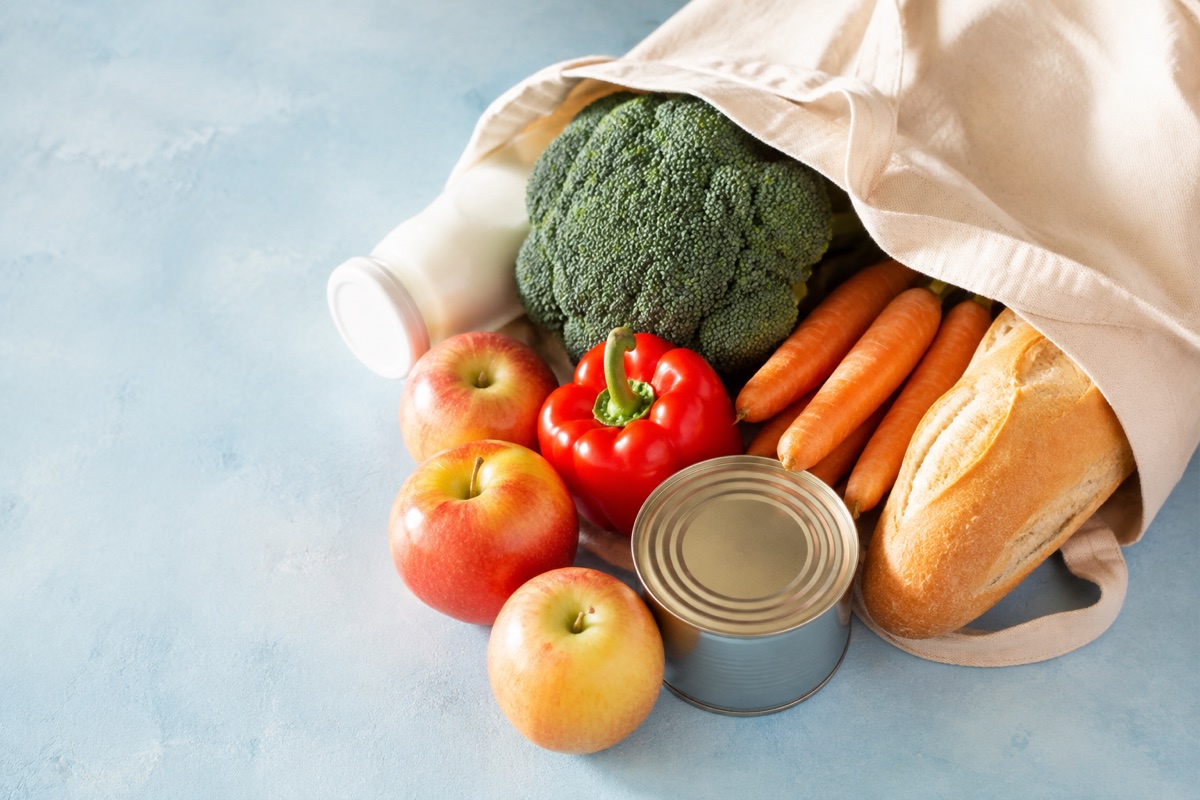 Fresh vegetables, apples, bread and milk in a reusable shopping bag